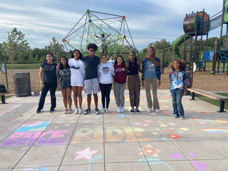 Expose Excellence student volunteers pose for a group photo in front of sidewalk chalk art